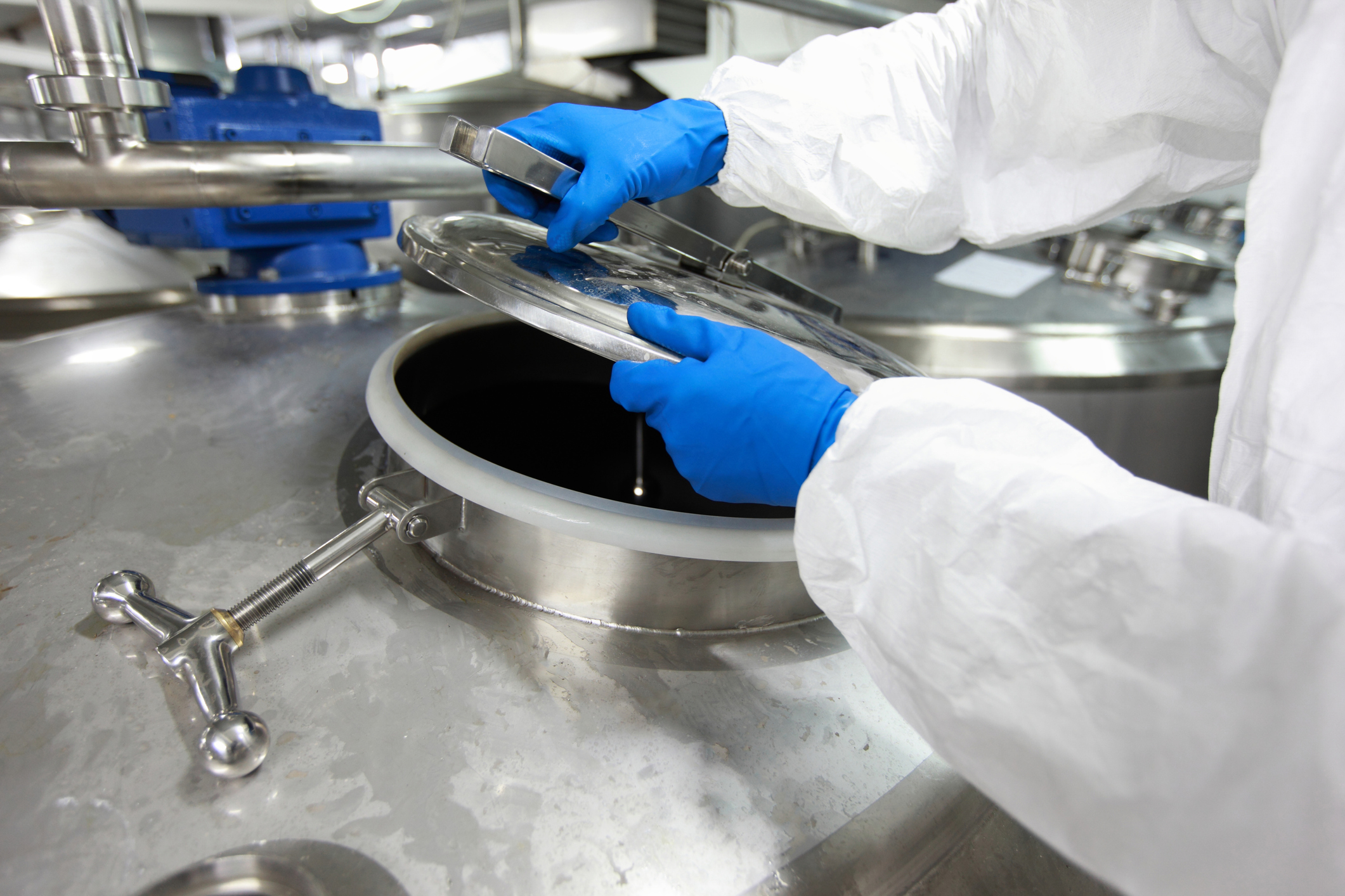 hands in gloves opening industrial process tank hands in gloves opening industrial process tank - close up