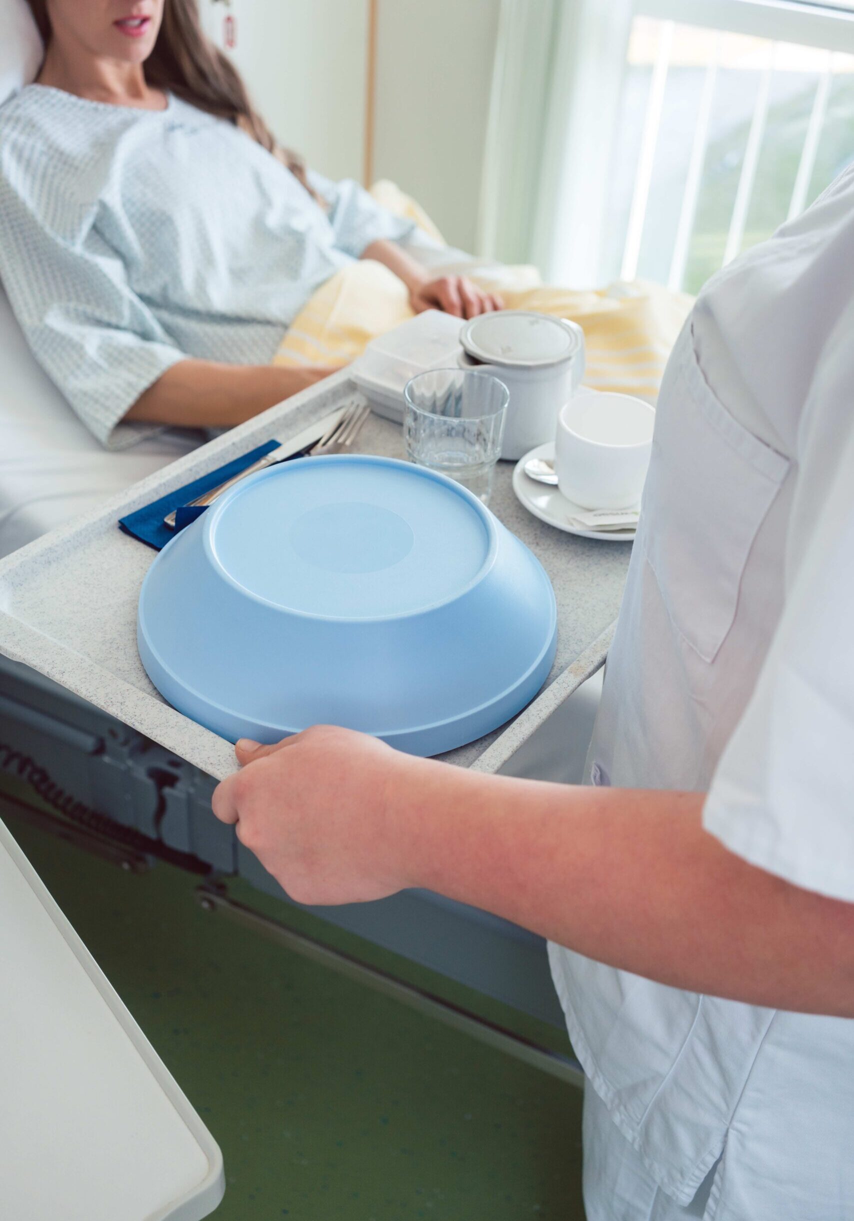 Nurse serving food in the hospital to a patient in bed Nurse serving food in the hospital to a patient in bed, top view